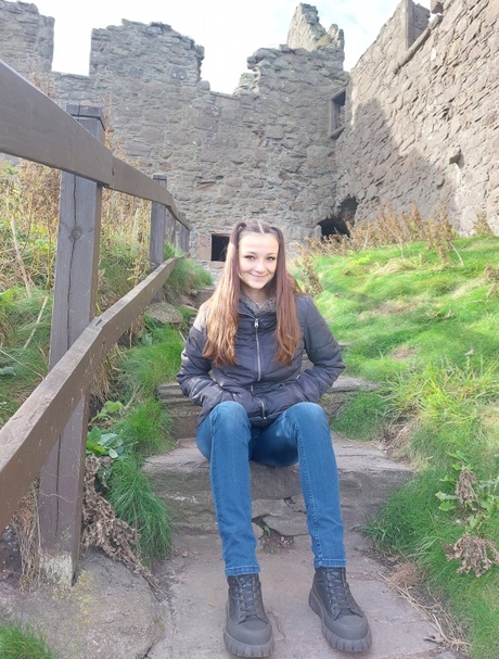 Kalina smiling, sitting in front of a ruined castle