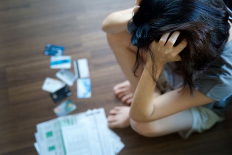 A woman gazing at credit cards with her head in her hands