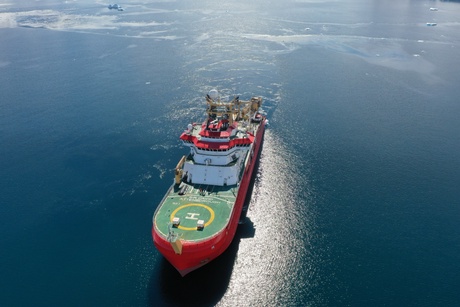 A ship in waters surrounded by snow covered mountains and glaciers