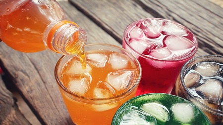 bottle of soft drink being poured into glasses