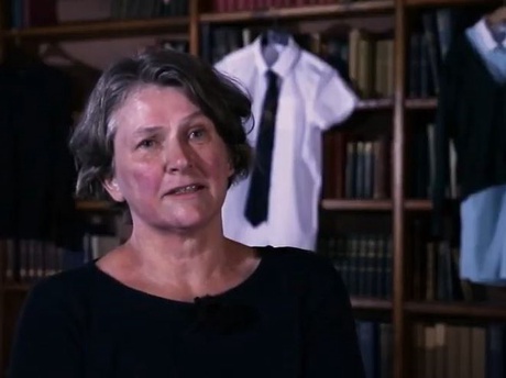 Dr Shanks in a library with school uniforms on display behind her