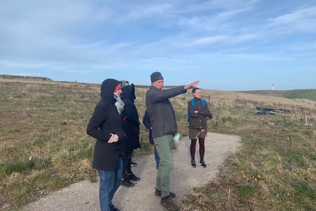 People standing on a hillside looking towards the site