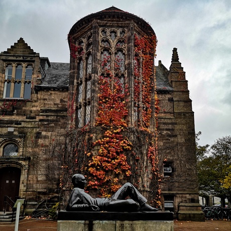 New Kings Building, covered in autumn foliage, with the young with a split apple sculpture in front.