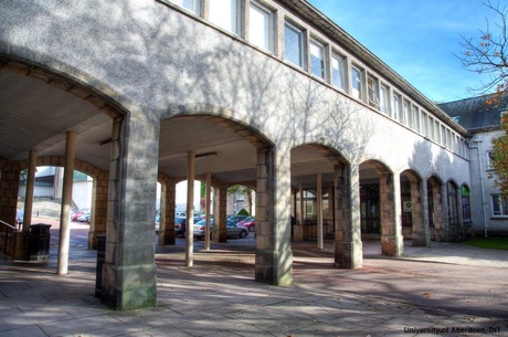 The Arches of Taylor Building, in the sun, with cars parked behind