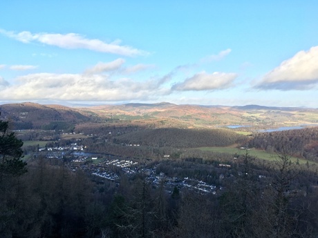 View from Birnam Hill. Birnam in the foreground, connected to Dunkeld by The Telford Bridge, with Loch of the Lowes in the distance basking in sunlight.