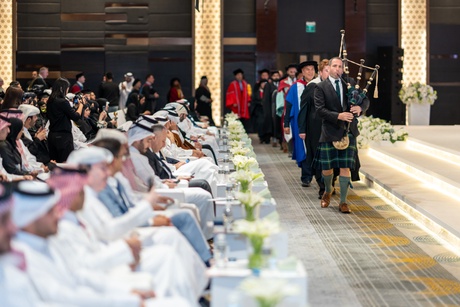 Academic procession being led into the ceremony by a bagpiper