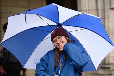 A member of staff smiling underneath an umbrella