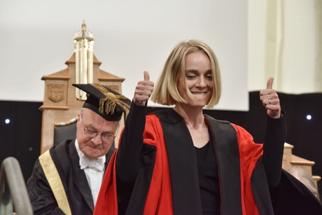 Woman giving two thumns up on the graduation stage