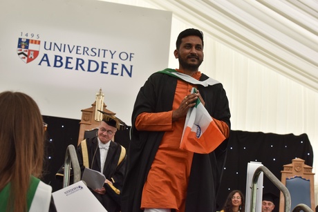 Man on stage carrying am Indian flag