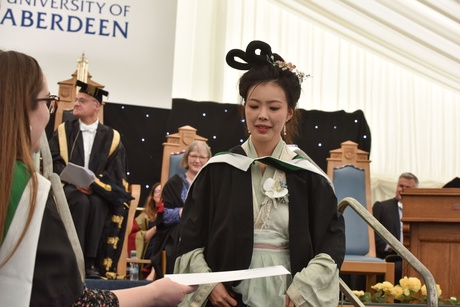 Woman in traditional Chinese dress accepting her certificate