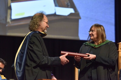 Honorary graduate, Colin Shepherd, being handed his scroll onstage