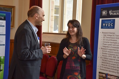 Two people talking with a research poster in the background