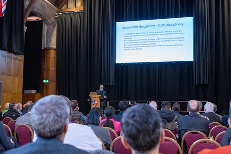 A man on stage speaking to an audience