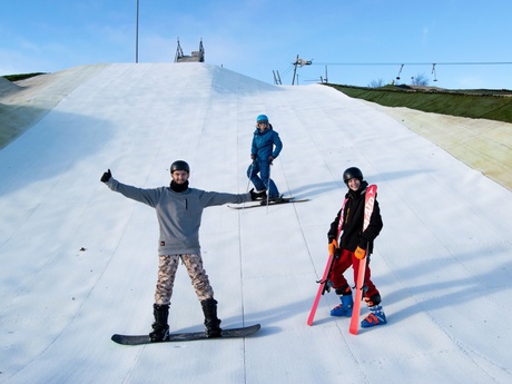 A man, a woman and a young person snowboarding on the dry ski slope in Aberdeen