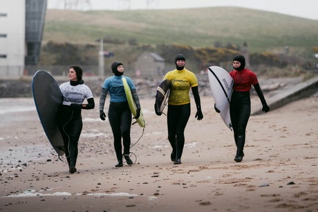 Surfers walking along the beach