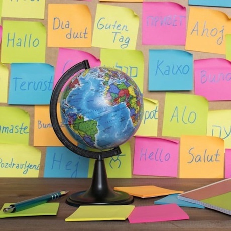 Globe with post-its on a wall behind it with the word 'hello' written on them in different foreign languages