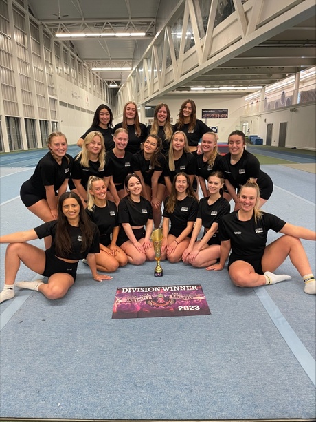 A photo of the AUSC Cheerleading Team gathered round their trophy and division winner certificate