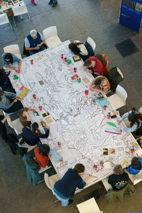 a photo taken from above of people colouring in a large map illustration