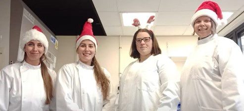 4 researchers with lab coats and santa hats