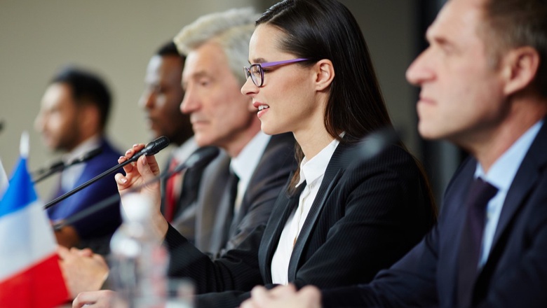 A panel of diverse speakers at the UN.  A woman with dark hair is in focus.