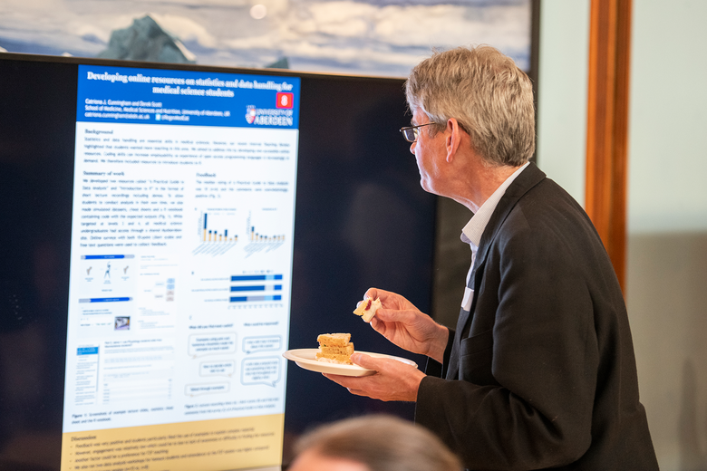 man reading one of the posters on screen at the symposium