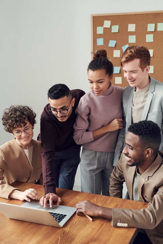 An ethnically mixed group of students stand around a computer